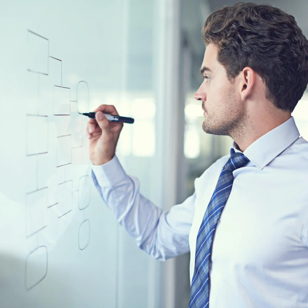 Business analyst drawing a workflow diagram on a glass board