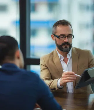 Man in a suit using a tablet during a meeting.