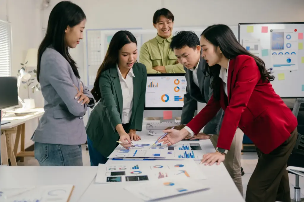 Creative team collaborating around a desk reviewing designs on a computer