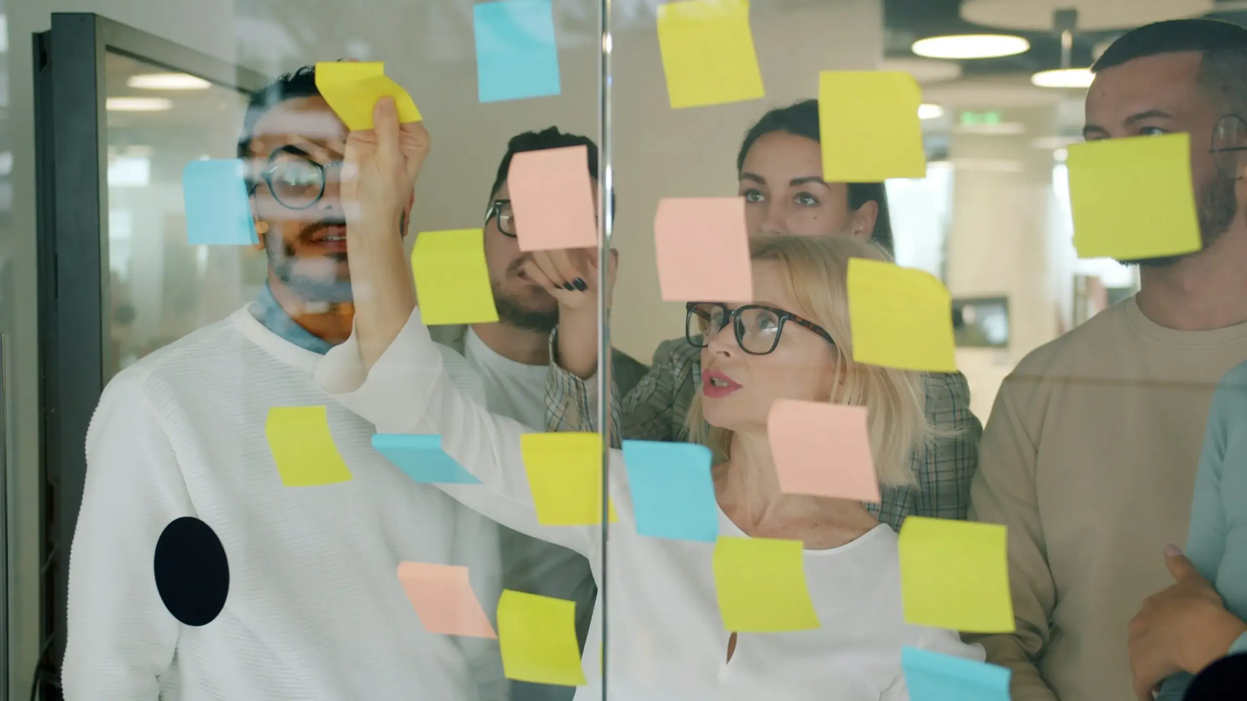 Team brainstorming ideas using sticky notes on a glass wall